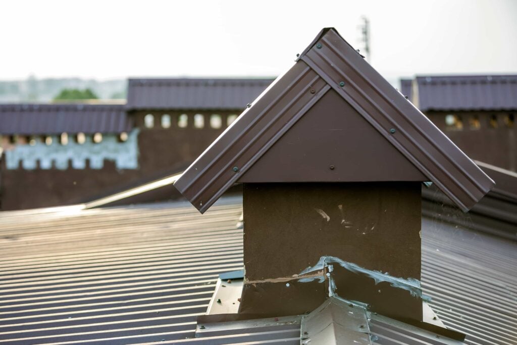 Preventative Home Maintenance to Protect Your Florida Property 2 A close-up view of a plastered brown chimney cap and damaged metal roof flashing with failing sealant, highlighting the need for expert chimney flashing repair service in Orlando, Florida.
